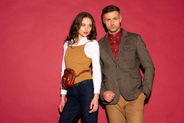 beautiful fashionable couple in formal wear posing on red background with copy space - Zdjęcie, obraz