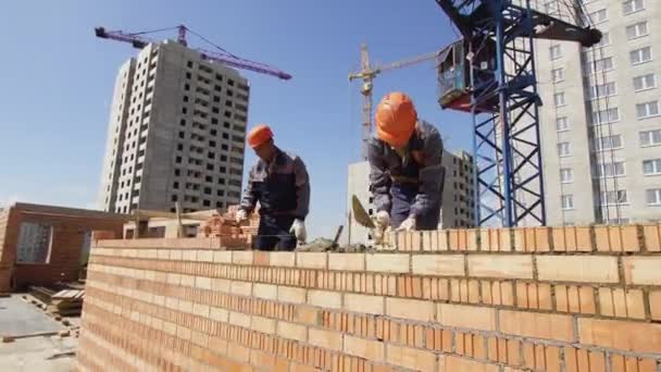 Minsk, Belarus, August 14 2018 - Worker lays bricks on a construction site. Brickwork industrial - Séquence, vidéo