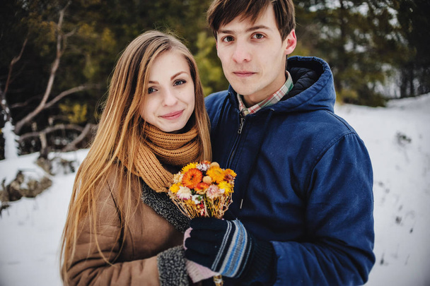 Young couple holding in hands bouquet dry flowers in winter landscape  - Photo, image