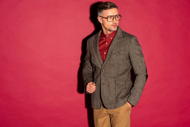 confident stylish man in formal wear and glasses on red background with copy space - Foto, Imagen