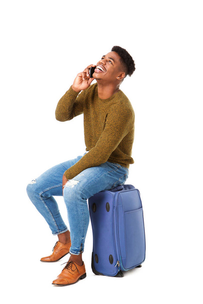 Podobizna muže šťastné cestování sedí hovoří s mobil a sedí na kufru izolované bílé pozadí - Fotografie, Obrázek