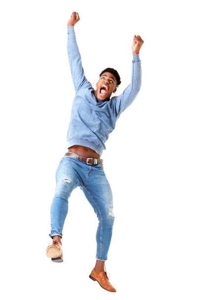Full body portrait of cheerful young black man jumping with arms raised against isolated white background - Foto, Bild