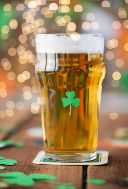 close up of glass of beer with shamrock on table - Fotó, kép