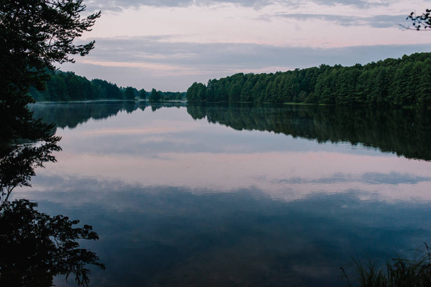 Panoramic view of tranquil forrest lake at pastel sunset - Foto, afbeelding