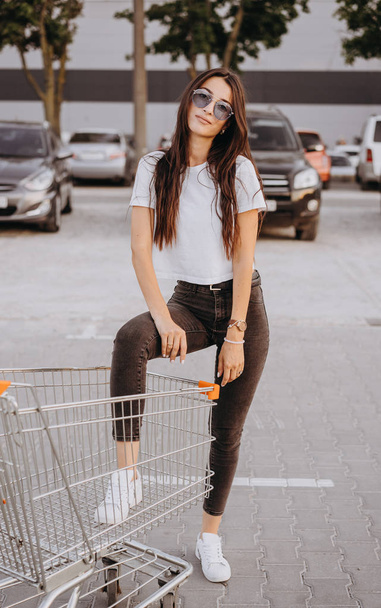 Mujer joven y feliz poner la pierna dentro de un carrito de compras
 - Foto, imagen