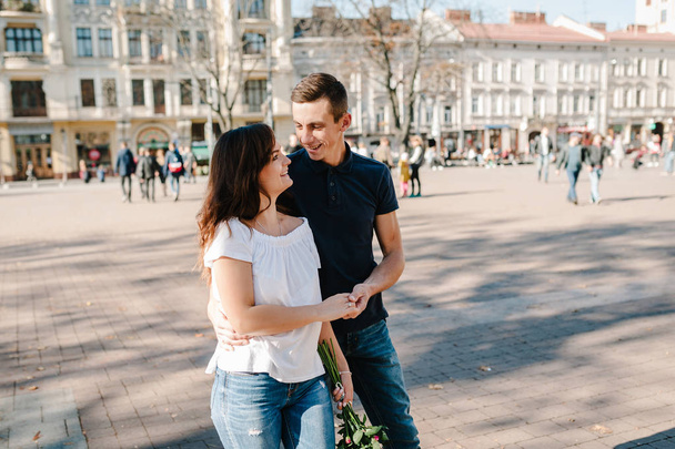 Young happy man and woman walking along streets of city - Фото, зображення