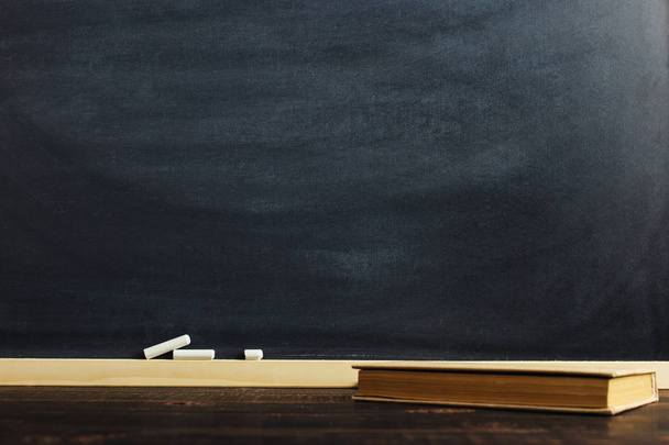 Черный мел на деревянном столе с книгой, пустой текст или фон для школьной темы
. - Фото, изображение