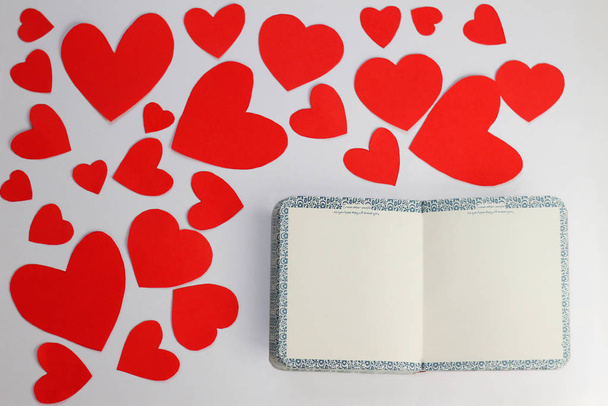 Valentines day background. Red hearts and empty letter on white paper background. Flat lay composition with copy space - 写真・画像