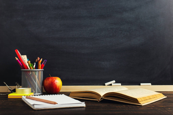 Lehrerpult mit Schreibmaterial, einem Buch und einem Apfel, einem Rohling für Text oder einem Hintergrund für ein Schulthema. Kopierraum. - Foto, Bild