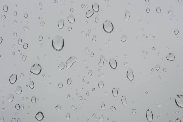 fond avec des gouttes de pluie sur un panneau de fenêtre dans un jour de pluie - Photo, image