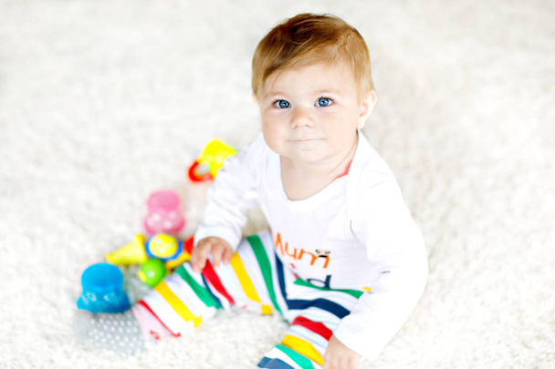 Adorable baby girl playing with educational toys in nursery. Happy healthy child having fun with colorful different toys at home. Baby development and first steps, learning to play and to grab. - Photo, Image