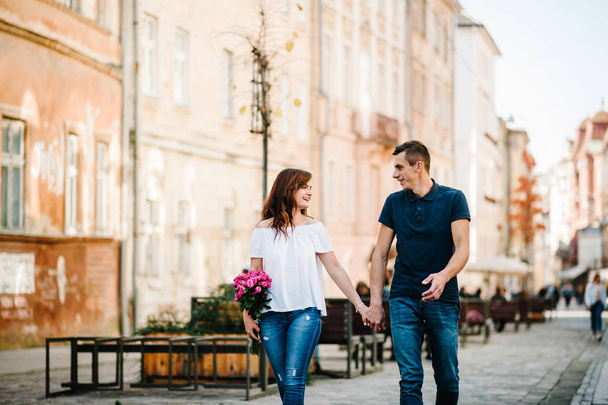 Young happy man and woman walking along streets of city - Foto, imagen