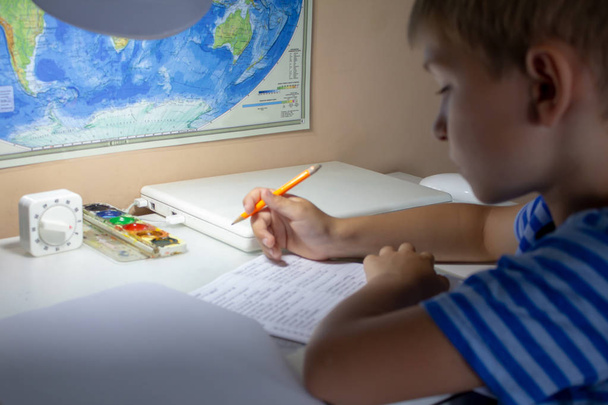 家庭教育。伝統的な白いメモ帳の紙に手で英語のテストを書くペンで少年の手。少年は、友人に手紙を書きます。放課後の家の仕事 - 写真・画像