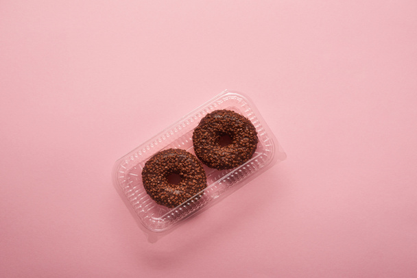 ピンクの背景のチョコレート ドーナツのトップ ビュー  - 写真・画像
