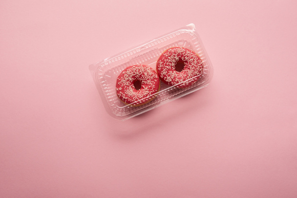 ピンクの背景の甘い艶をかけられたドーナツのトップ ビュー  - 写真・画像