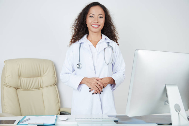 Ritratto di specialista in medicina asiatica sorridente in piedi vicino al suo posto di lavoro con computer in ufficio
 - Foto, immagini