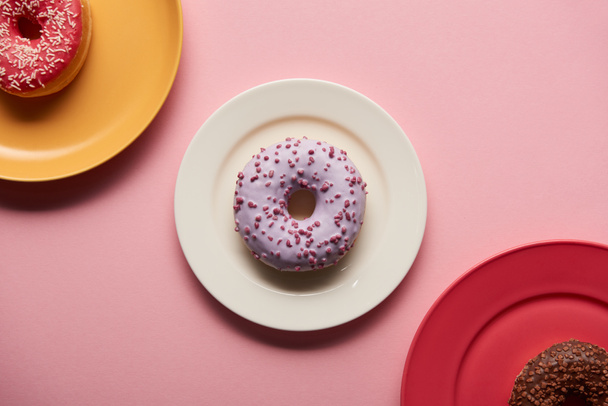 top view of sweet donuts on plates on pink background - Foto, Imagen