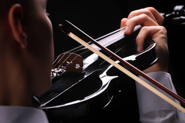 Young men playing the violin with black background - Photo, Image