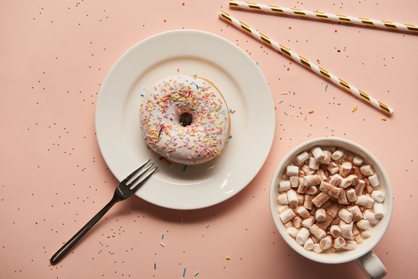вид сверху на сладкое какао с зефиром рядом с пончиком на розовом фоне
  - Фото, изображение