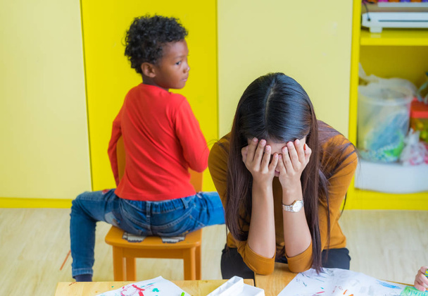 Teacher get headache with two naughty kids in classroom at kindergarten school - Fotoğraf, Görsel