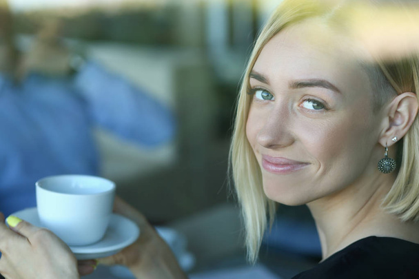 Woman blonde talking to friends in a cafe for a cup of coffee - Photo, image