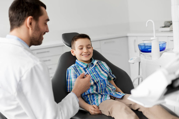 dentist giving toothbrush to kid patient at clinic - Zdjęcie, obraz