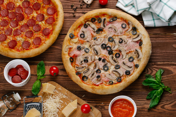 pohled shora ze dvou vařené pizzy na dřevěný stůl - Fotografie, Obrázek