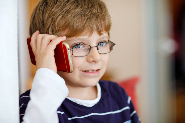 cuki kisfiú, szemüveges, mobilon beszél. Imádnivaló egészséges gyermek gazdaság smartphone és beszél egy lány barátja, vagy a szülők, nagyszülők. - Fotó, kép