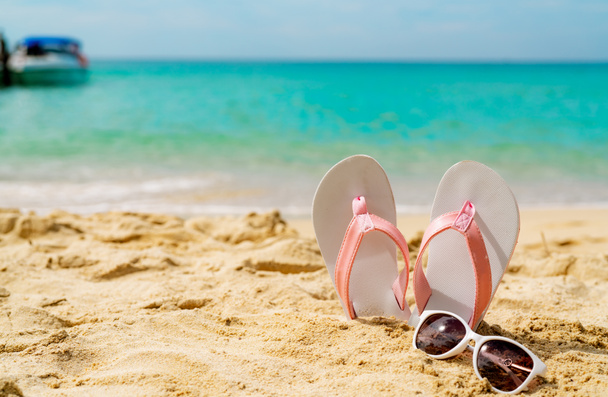 Rózsaszín és fehér szandál, napszemüveg, a homok a tengerparton. Alkalmi divat stílus flipflop és szemüveg tengerparton. A trópusi tengerparti nyaralás. Szórakoztató nyaralás, homokos tengerparton. Nyáron. - Fotó, kép