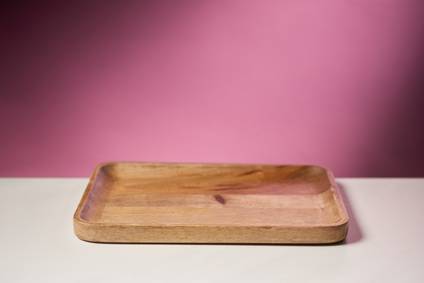 tabla de cortar de madera sobre mesa blanca sobre fondo rosa
 - Foto, Imagen