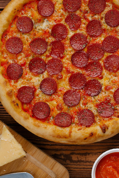 вид зверху вареної піци з томатним соусом, сиром і нарізаними ковбасками на дерев'яному столі
 - Фото, зображення