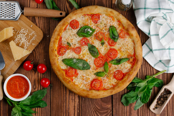 vista superior de la pizza con tomates, queso y hojas de albahaca fresca servidas en mesa de madera
 - Foto, imagen
