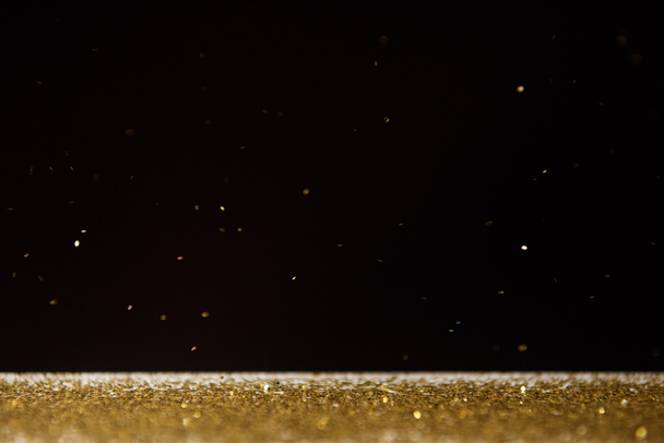  table with bright golden sparkles isolated on black  - Φωτογραφία, εικόνα