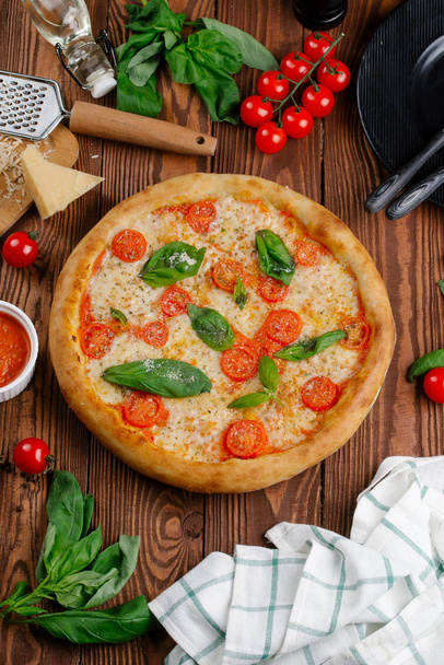 vista superior de pizza com tomate, queijo e folhas de manjericão fresco servido em mesa de madeira
 - Foto, Imagem