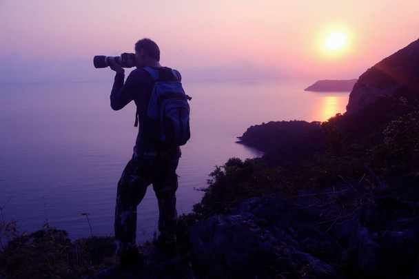 Silhouette purple of man climbing rock, Photographer on the mountain at sunrise,Archipelago island in Thailand - Photo, Image