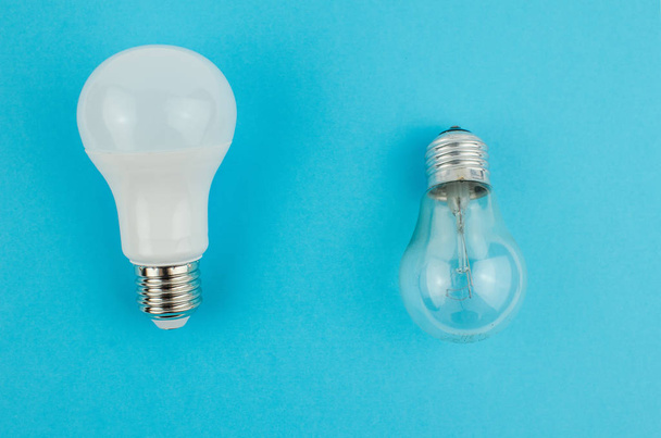 incandescent lamp and energy saving on a blue background. Copy space - Photo, Image
