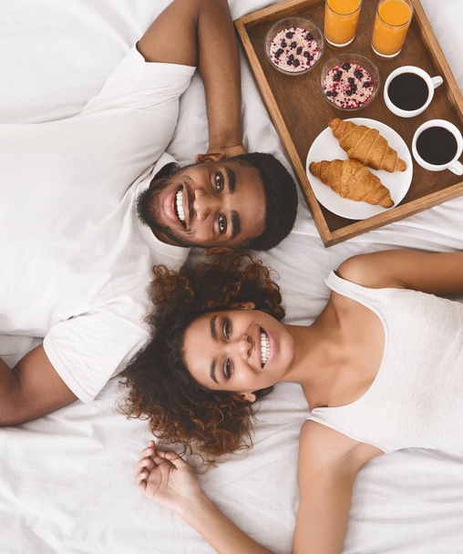 Feliz pareja joven desayunando en la cama por la mañana
 - Foto, imagen