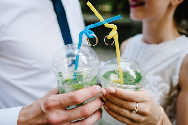 man and woman holding plastic glasses of lemonade with two wedding rings - Foto, immagini