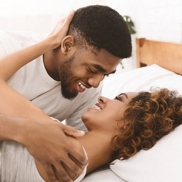 Αγαπώντας μαύρο ζευγάρι χαλαρώνετε στο κρεβάτι στο σπίτι, - Φωτογραφία, εικόνα
