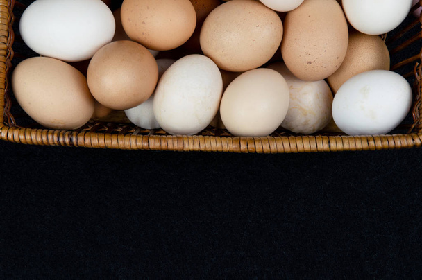 Top näkymä kananmunat korissa mustalla pohjalla
 - Valokuva, kuva