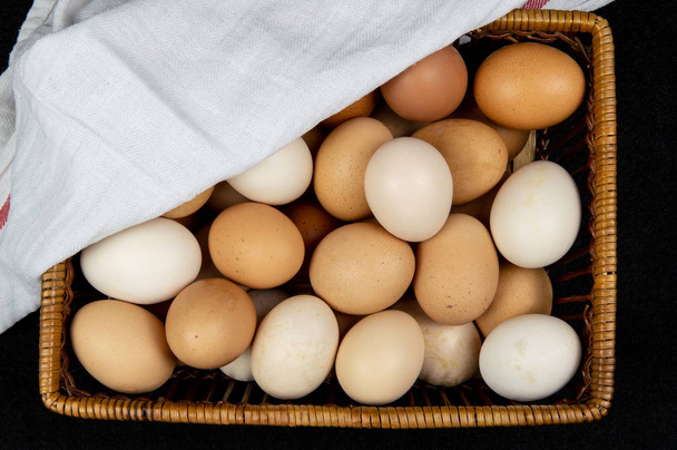 Vista superior de ovos de galinha em uma cesta em um fundo preto
 - Foto, Imagem