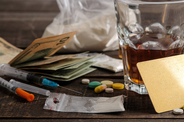 Auf einem braunen Holztisch liegen verschiedene Suchtmittel wie Alkohol, Zigaretten und Drogen. Drogenabhängiges Konzept - Foto, Bild