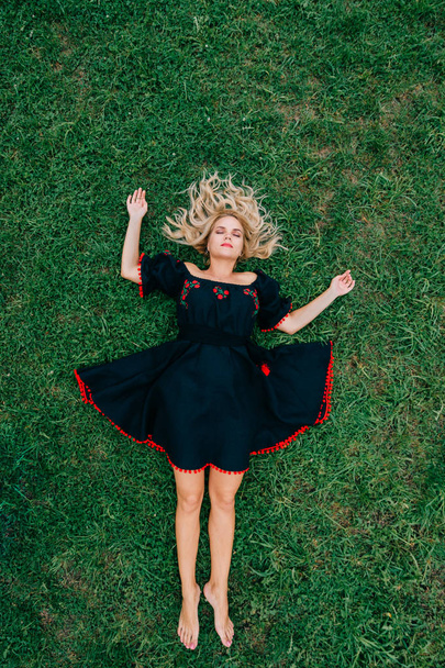 overhead view of beautiful woman in black dress resting on green grass - Foto, Imagem