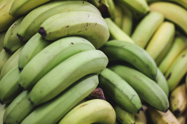 Pile of green bananas on the farmers market or shop, organic food, fruit background - Photo, Image