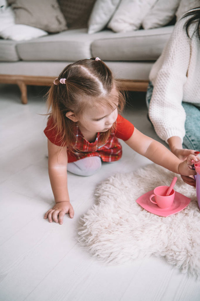 Little girl playing toy baby dishes at home - 写真・画像