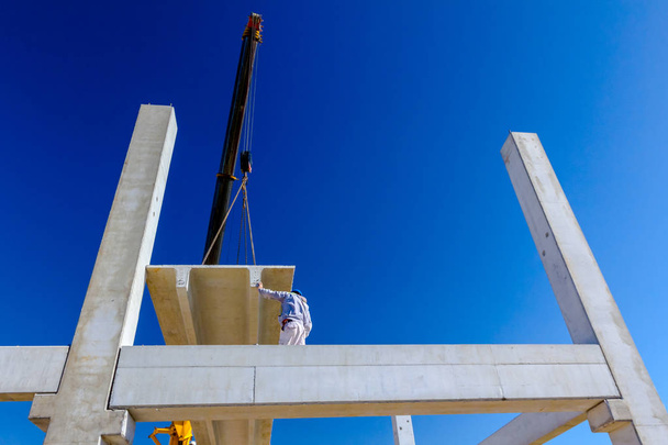Trabalhador está ajudando guindaste móvel para gerenciar viga de concreto para montagem construção enorme
. - Foto, Imagem