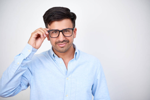 Portrait of confident young businessman with dark hair and stubble looking at you through his eyeglasses isolated on white background - Foto, afbeelding