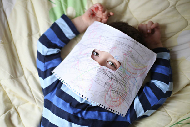 Ritratto di un ragazzo che si copre il viso con la sua opera d'arte
 - Foto, immagini