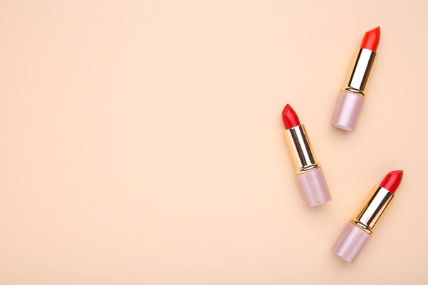 Three colorful lipsticks on beige background. Cosmetic, macro - Photo, Image