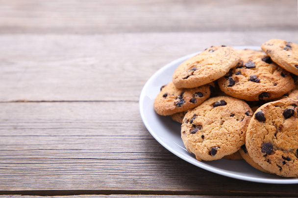 Chocolate chip cookies on plate on grey wooden table - Foto, imagen